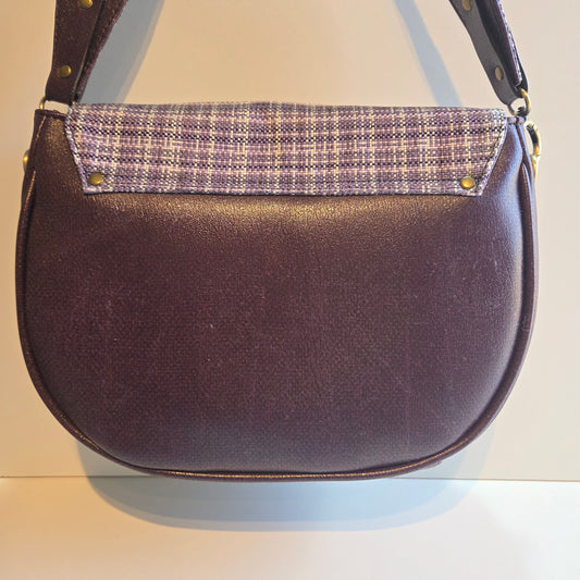 Back view of a purple shoulder bag with a purple and white plaid fabric accent and antique brass hardware