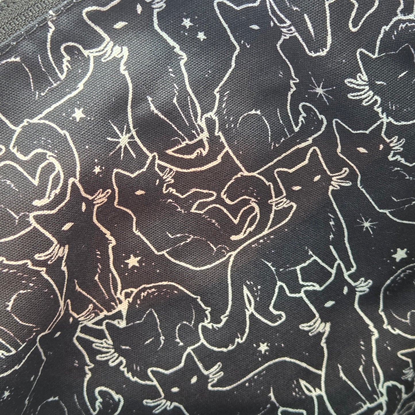 lining fabric with pattern of white cat outlines and stars on a black background