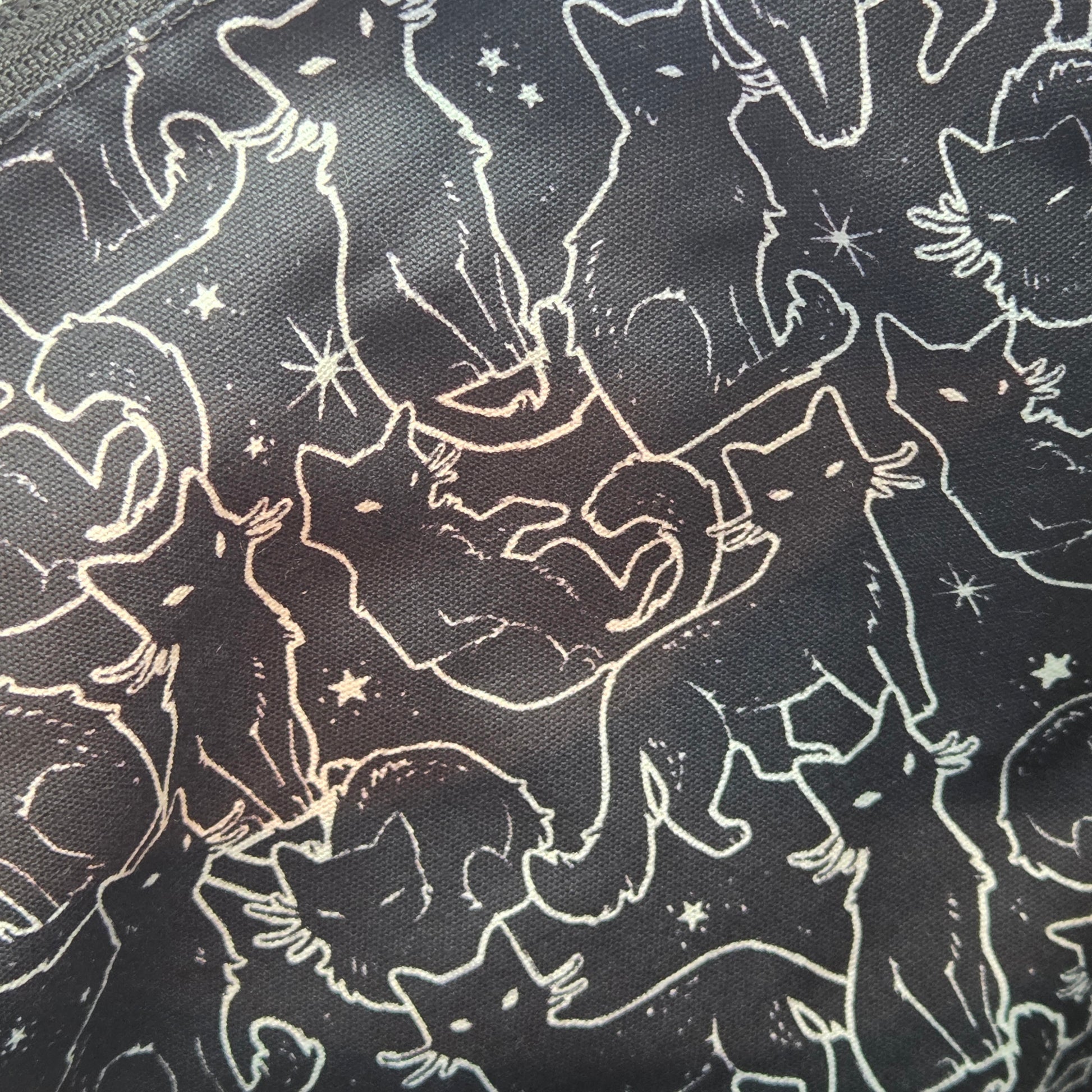lining fabric with pattern of white cat outlines and stars on a black background