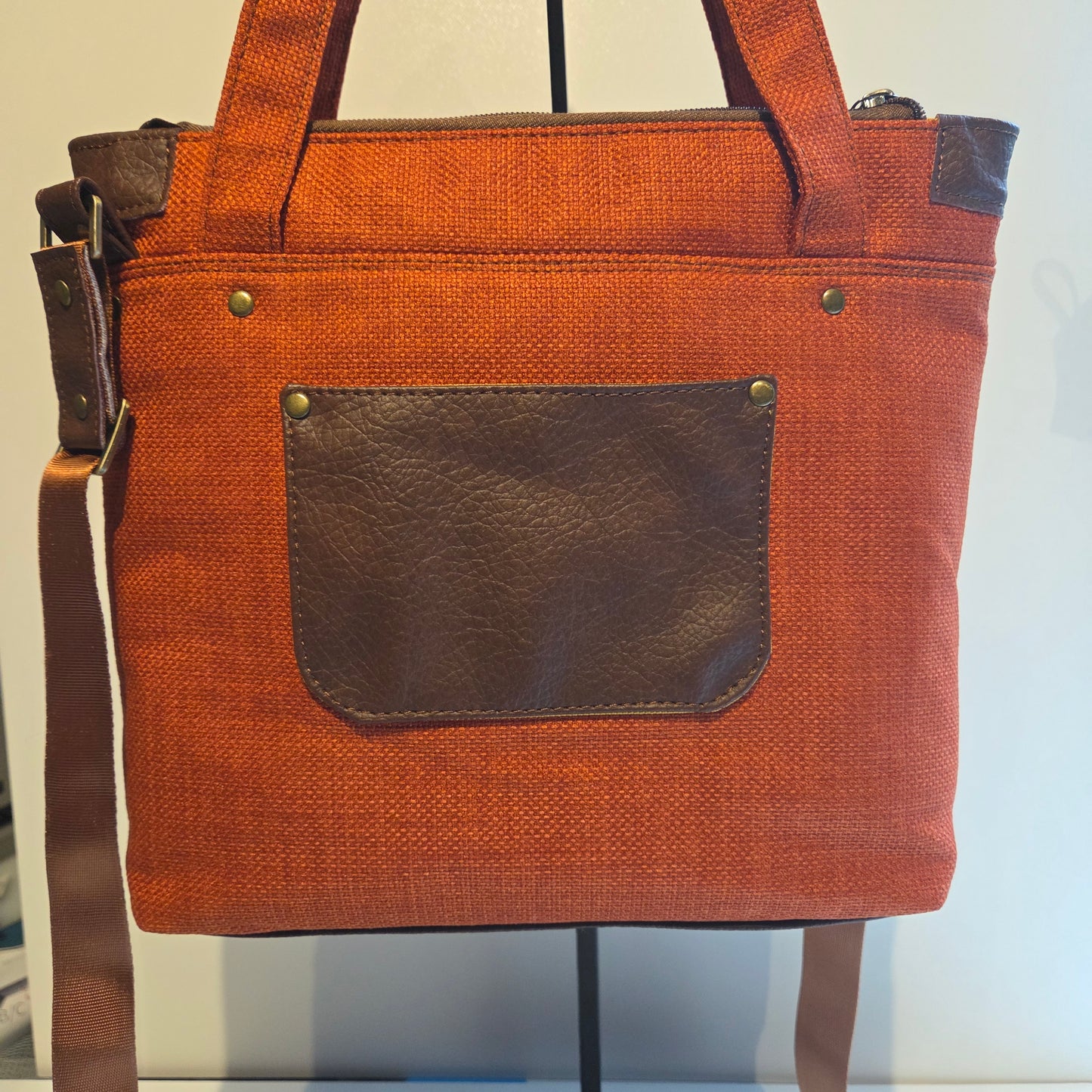 Back view of an orange tote bag with brow pocket and brass hardware