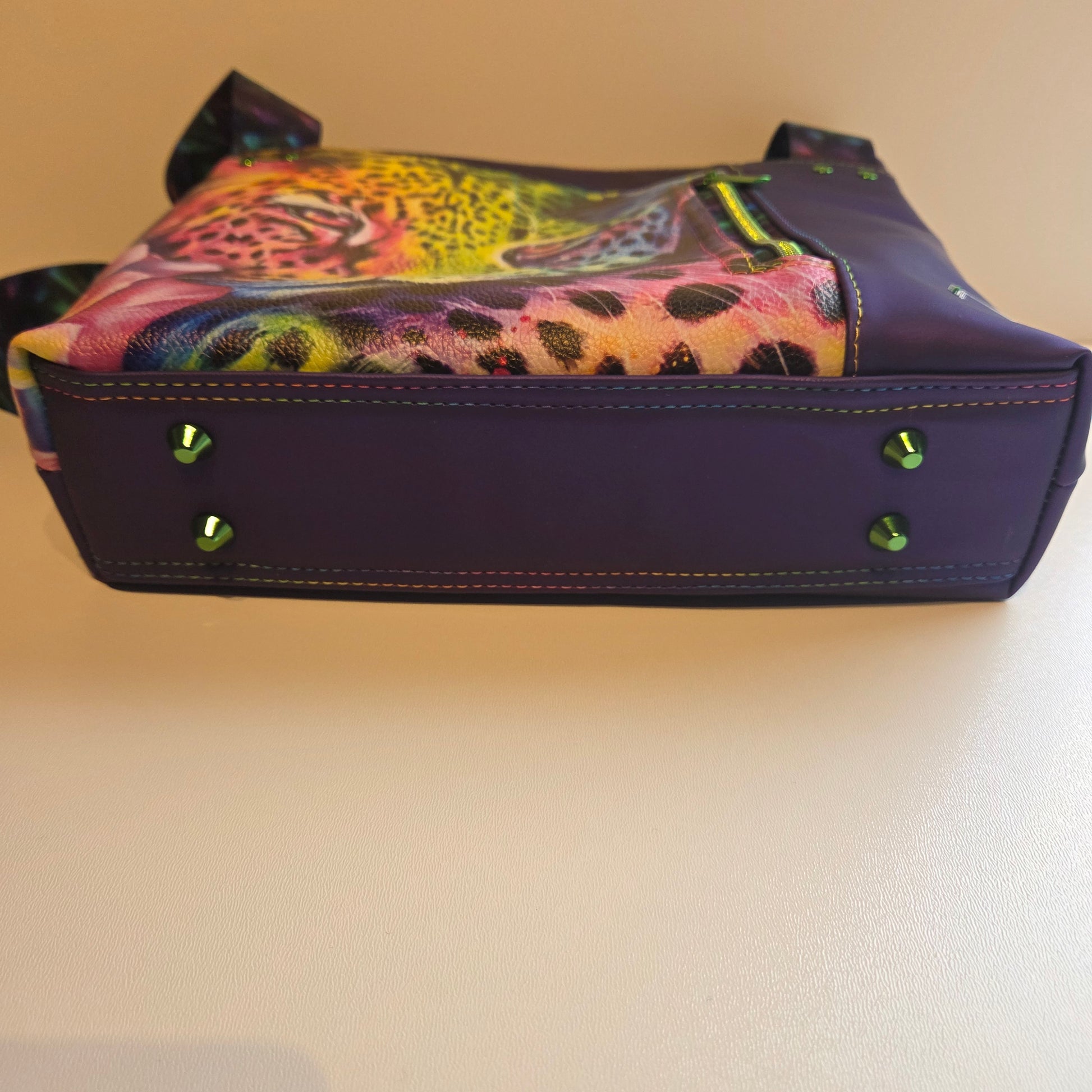 Base of purple tote bag with green hardware and rainbow stitching detail