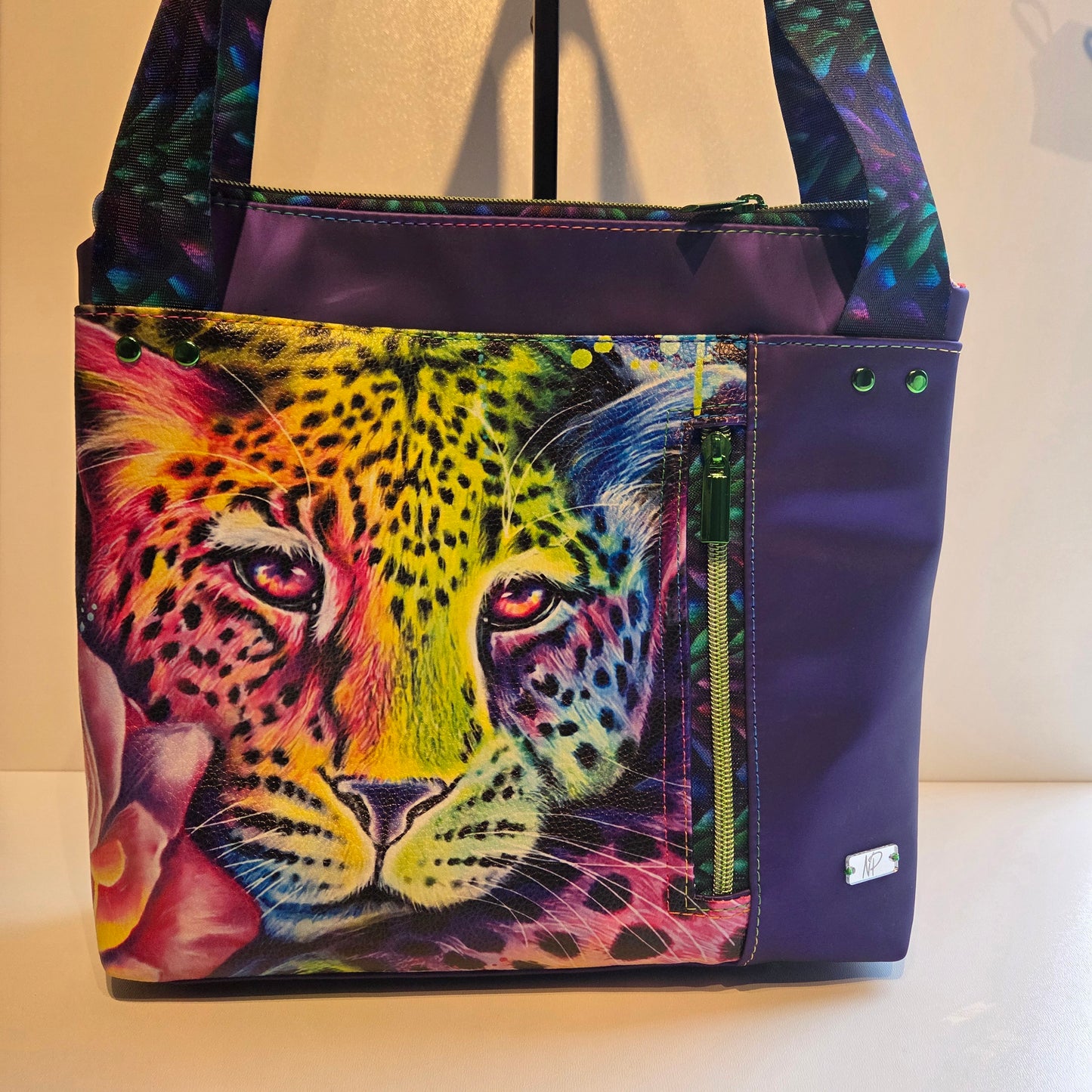 Purple tote bag with a Colourful leopard design and green hardware. 