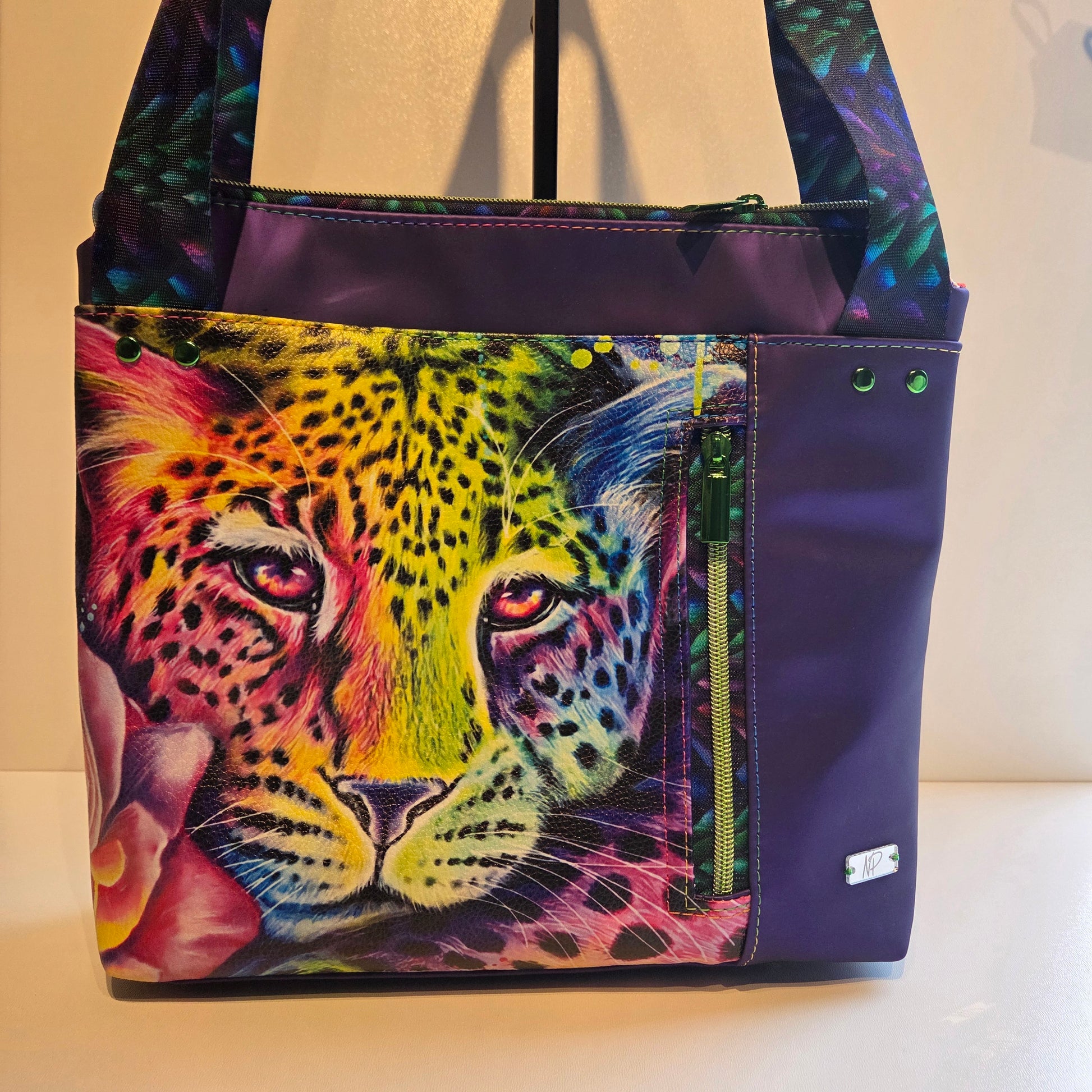 Purple tote bag with a Colourful leopard design and green hardware. 